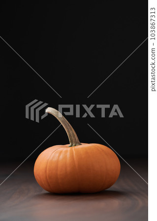 Small orange pumpkin on black walnut table with copy space Small orange pumpkin on black walnut table with copy space 103867313
