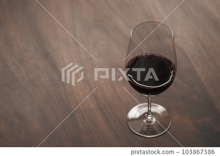 Red wine in wineglass on black walnut table with copy space Red wine in wineglass on black walnut table with copy space 103867386