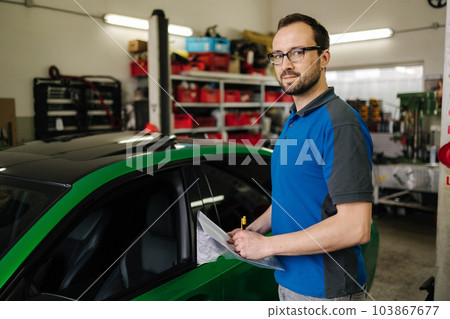 Portrait of male owner of car repair shop. Mechanic detailed vehicle inspection. Auto service centre concept 103867677