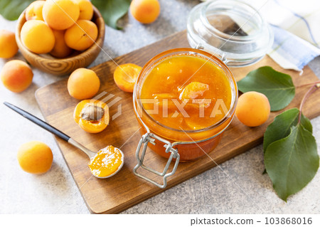 Homemade preservation. Delicious apricots jam or jelly on a stone table. Homemade preservation. Delicious apricots jam or jelly on a stone table. 103868016