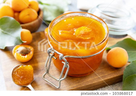 Delicious apricots jam or jelly on a stone table. Homemade preservation. Delicious apricots jam or jelly on a stone table. Homemade preservation. 103868017