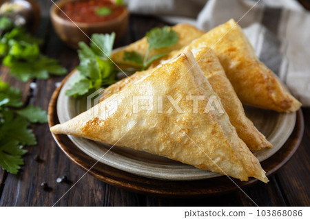 Asian food. Vegetarian samsa (samosas) with tomato sauce on a wooden table. Popular in Indonesia as Risoles Sayur. Asian food. Vegetarian samsa (samosas) with tomato sauce on a wooden table. Popular in Indonesia as Risoles Sayur. 103868086