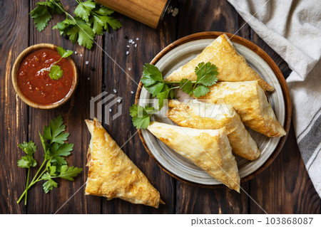 Asian food. Vegetarian samsa (samosas) with tomato sauce on a wooden table. Popular in Indonesia as Risoles Sayur. View from above. Asian food. Vegetarian samsa (samosas) with tomato sauce on a wooden table. Popular in Indonesia as Risoles Sayur. View from above. 103868087