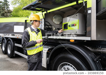 Worker with digital tablet operating construction machine 103869150