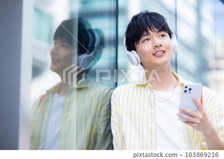 Young man listening to music with smartphone headphones Young man listening to music with smartphone headphones 103869216