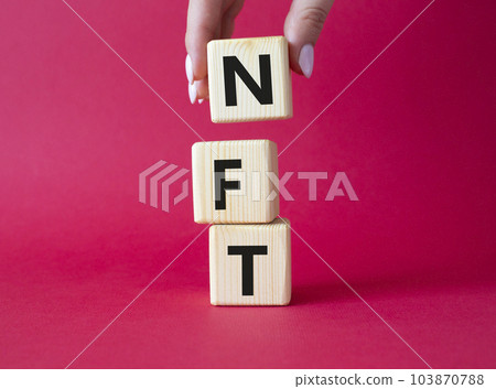 NFT - non-fungible token symbol. Concept word NFT on wooden cubes. Businessman hand. Beautiful red background. Business and NFT concept. Copy space. NFT - non-fungible token symbol. Concept word NFT on wooden cubes. Businessman hand. Beautiful red background. Business and NFT concept. Copy space. 103870788