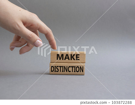 Make distinction symbol. Concept words make distinction on wooden blocks. Beautiful grey background. Businessman hand. Business and make distinction concept. Copy space. Make distinction symbol. Concept words make distinction on wooden blocks. Beautiful grey background. Businessman hand. Business and make distinction concept. Copy space. 103872288