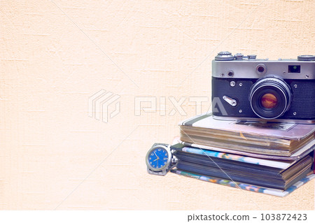 Old vintage film photo camera with photo album and watch isolated on pale pink Old vintage film photo camera with photo album and watch isolated on pale pink 103872423