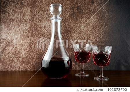 Wine Decanter and Wine Glasses with Wine on a Polished Wooden Table Top 103872700