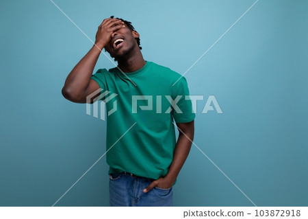 handsome american young man in casual green t-shirt on blue background handsome american young man in casual green t-shirt on blue background 103872918