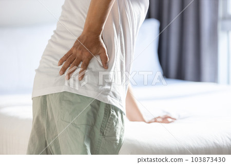 Middle aged man touching his hip,backache while standing or walking,symptom of chronic muscle injury,Stressed asian people suffering from sore waist,back pain and stretching,healthcare,medical concept 103873430