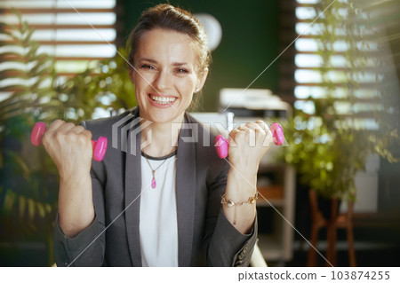 happy modern business woman at work with dumbbells happy modern business woman at work with dumbbells 103874255
