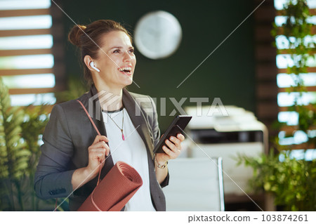 smiling business woman in green office using smartphone app 103874261
