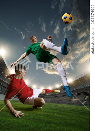 Concentration and winning goal. Two male sportsmen, football players in motion during competition, playing at 3D openair stadium Concentration and winning goal. Two male sportsmen, football players in motion during competition, playing at 3D openair stadium 103874993