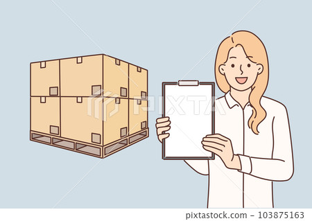 Woman logistician stands near boxes placed on pallet and demonstrates empty clipboard 103875163