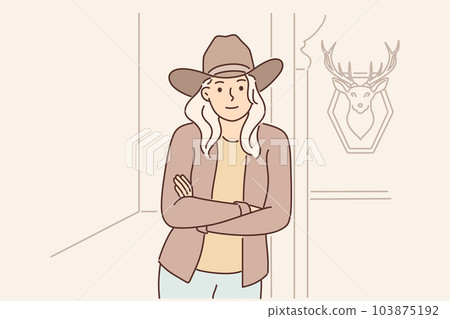 Woman ranger and ranch owner stands with arms crossed near wall with stuffed deer Woman ranger and ranch owner stands with arms crossed near wall with stuffed deer 103875192