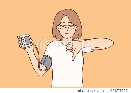 Woman holding tonometer to check cardio health and heart disease shows thumb down 103875232