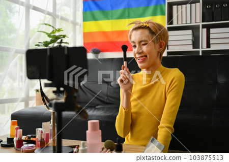 Charming young gay man blogger recording make up tutorial, live streaming at home. LGBTQ lifestyle, influencer, blogger Charming young gay man blogger recording make up tutorial, live streaming at home. LGBTQ lifestyle, influencer, blogger 103875513