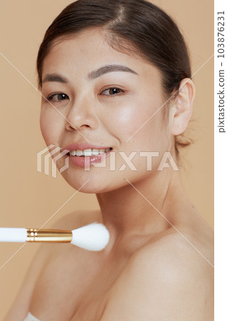 Portrait of young woman with makeup brush Portrait of young woman with makeup brush 103876231