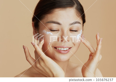 Portrait of young woman with facial cream on face 103876237