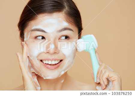 young woman with massager washing face 103876250