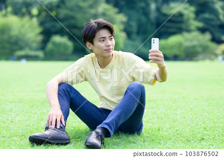 man looking at smartphone on lawn 103876502