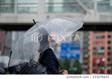 Profile of a woman holding an umbrella and walking in a rainy city Profile of a woman holding an umbrella and walking in a rainy city 103876695