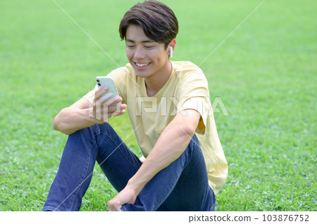 坐在草地上聽音樂的年輕人 坐在草地上聽音樂的年輕人 103876752