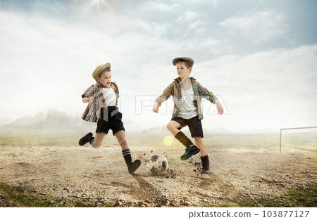 Active little boys, children in retro style clothes playing football outdoors on a daytime. warm sunny day on countryside 103877127