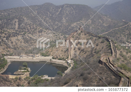 Sagar Lake and fortification wall of Jaigarh Fort situated on Cheel ka Teela or Hill of Eagles of the Aravalli range, it overlooks the Amer Fort and the Maota Lake, near Amer Jaipur, Rajasthan, India 103877372