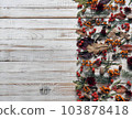 Space for text.Autumn.Background from medicinal berries of sea buckthorn,barberry,rowanberry, nuts and plant twigs on a white wooden table. 103878418
