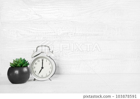 Front view white desk with alarm clock, houseplant and copy space. Morning background banner with free space for text. Minimalistic concept, workspace, time to work. Blank workplace. Office mock-up Front view white desk with alarm clock, houseplant and copy space. Morning background banner with free space for text. Minimalistic concept, workspace, time to work. Blank workplace. Office mock-up 103878591