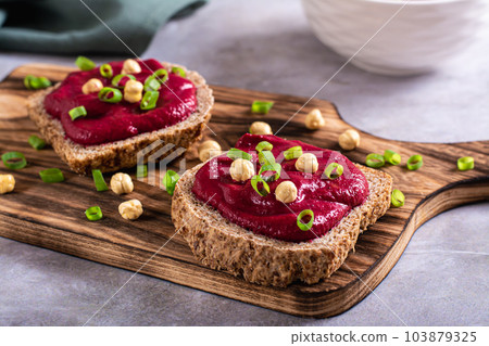 Homemade rye bread sandwiches with beetroot hummus and herbs on a cutting board Homemade rye bread sandwiches with beetroot hummus and herbs on a cutting board 103879325