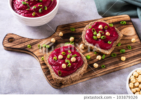 Appetizing rye bread bruschettas with beetroot hummus and chives on a cutting board Appetizing rye bread bruschettas with beetroot hummus and chives on a cutting board 103879326