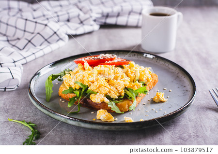 Appetizing toast with scrambled egg, tomato and sesame seeds on a plate 103879517
