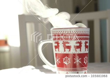 Steaming Cup of Coffee or Tea on Table. Close up ceramic red Christmas mug with smoke. Hot Drink. Steaming Cup of Coffee or Tea on Table. Close up ceramic red Christmas mug with smoke. Hot Drink. 103881068
