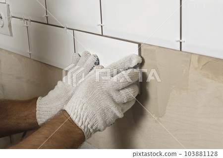 Male Worker Master Laying Ceramic Tiles on the Wall of Kitchen. Repairman Placing White Modern Tiles, Spreading Adhesive. Builder Installing Tile at Repair Renovation Work. Professional Tiling. 4K Male Worker Master Laying Ceramic Tiles on the Wall of Kitchen. Repairman Placing White Modern Tiles, Spreading Adhesive. Builder Installing Tile at Repair Renovation Work. Professional Tiling. 4K 103881128