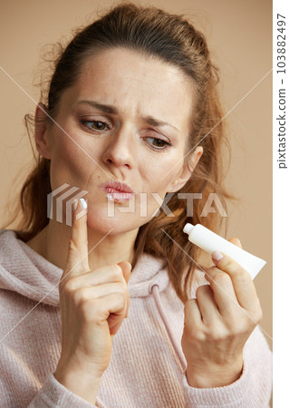 female applying ointment using finger isolated on beige female applying ointment using finger isolated on beige 103882497