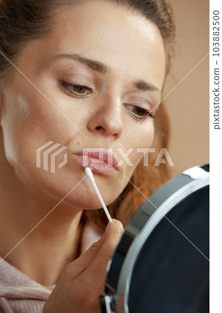 woman applying ointment using cotton swab isolated on beige woman applying ointment using cotton swab isolated on beige 103882500