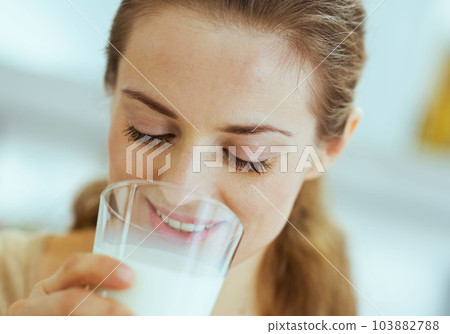 Young woman drinking milk in kitchen 103882788