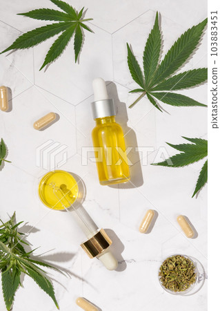 Dropper bottle with CBD oil, pipette and capsules near cannabis leaves top view, hard shadows Dropper bottle with CBD oil, pipette and capsules near cannabis leaves top view, hard shadows 103883451