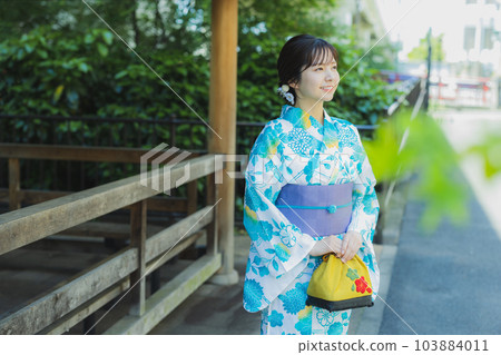A woman in a yukata walking outdoors 103884011