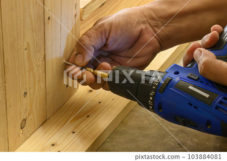 The carpenter using the cordless screwdriver with wood board. 103884081