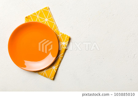 Top view on colored background empty round red plate on tablecloth for food. Empty dish on napkin with space for your design Top view on colored background empty round red plate on tablecloth for food. Empty dish on napkin with space for your design 103885010