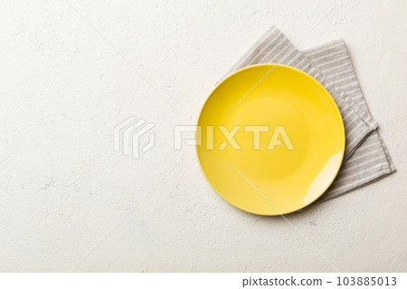 Top view on colored background empty round yellow plate on tablecloth for food. Empty dish on napkin with space for your design Top view on colored background empty round yellow plate on tablecloth for food. Empty dish on napkin with space for your design 103885013