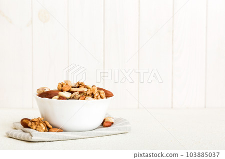 mixed nuts in bowl. Mix of various nuts on colored background. pistachios, cashews, walnuts, hazelnuts, peanuts and brazil nuts mixed nuts in bowl. Mix of various nuts on colored background. pistachios, cashews, walnuts, hazelnuts, peanuts and brazil nuts 103885037