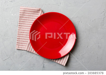 Top view on colored background empty round red plate on tablecloth for food. Empty dish on napkin with space for your design Top view on colored background empty round red plate on tablecloth for food. Empty dish on napkin with space for your design 103885378