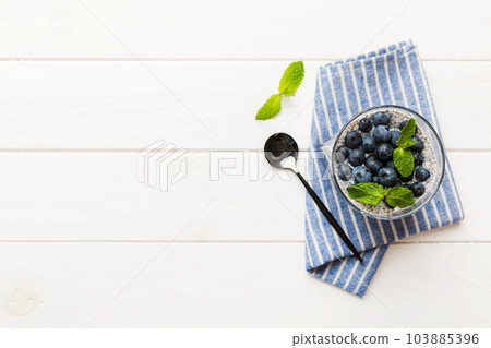 Healthy breakfast or morning with chia seeds vanilla pudding and blueberry berries on table background, vegetarian food, diet and health concept. Chia pudding with coconut milk and blueberry 103885396