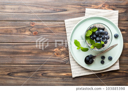 Healthy breakfast or morning with chia seeds vanilla pudding and blueberry berries on table background, vegetarian food, diet and health concept. Chia pudding with coconut milk and blueberry 103885398