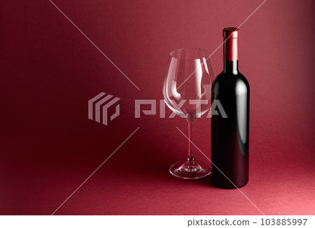 Bottle and glass of red wine on a red background. 103885997